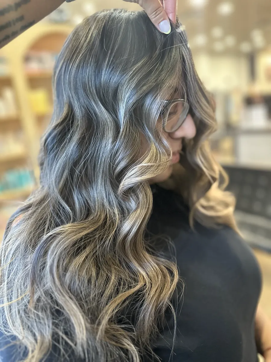 Balayage blond lumineux sur cheveux ondulés, réalisé au Studio Délia à Laval